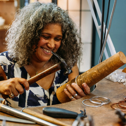 Woman hammer texturing a bangle