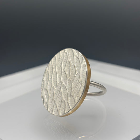 Silver ring with a textured design on a reflective surface