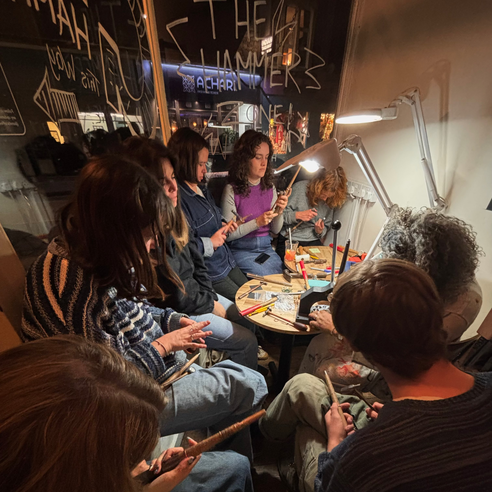 Group of people sitting around a table in a workshop.